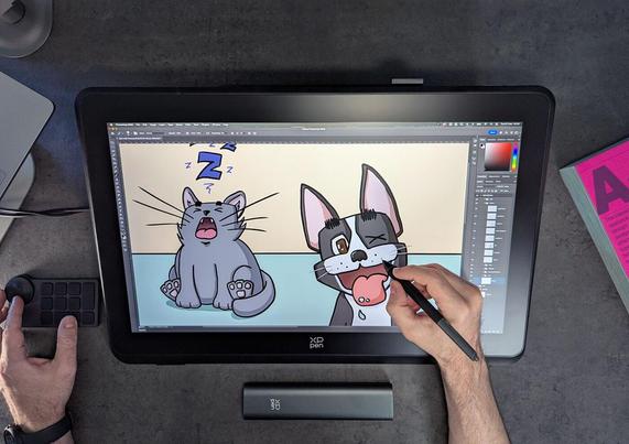 Person drawing a cartoon of a cat and a dog on a digital tablet with a stylus, surrounded by drawing tools and a book on a desk.