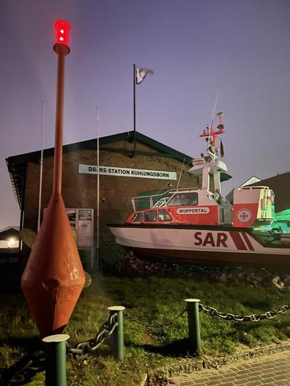 Night time shot of the original DGzRS station, with a small rescue boat in the front.