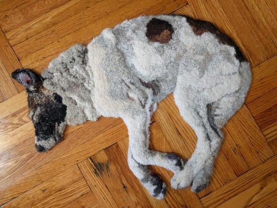 a realistic relief textile work of a dog lounging on a wooden floor, made via rug hooking