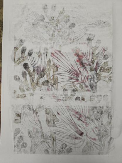 The back of a printed paper, glued with medium onto a piece of glass which is not visible because it's obscured by the paper. 
The middle and bottom of the paper is more transparent than the top, and an image of fish and aquatic plants in an art nouveau style can be glimpsed.