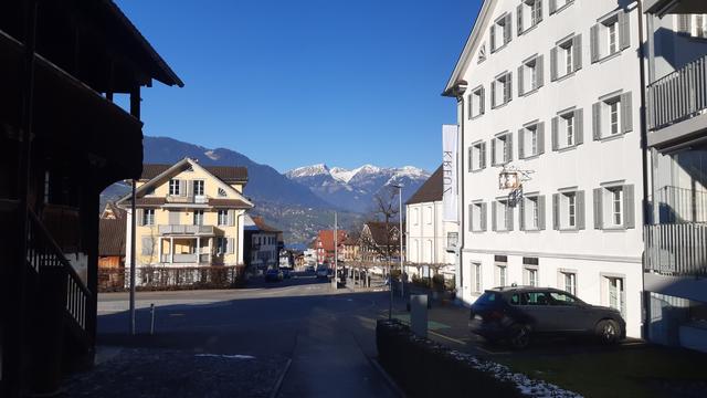 Sicht zwischen Häusern auf Berge mit Schnee auf Spitze