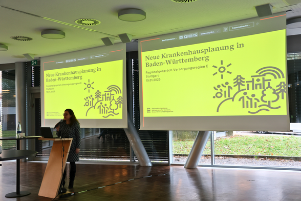 Ministerialdirektorin Leonie Dirks spricht in ein Mikrofon. Im Hintergrund sieht man an einer Leinwand eine Powerpoint-Präsentation. Darauf steht: Neue Krankenhausplanung in Baden-Württemberg. Regionalgespräch Versorgungsregion E Stuttgart. 15.01.2025.