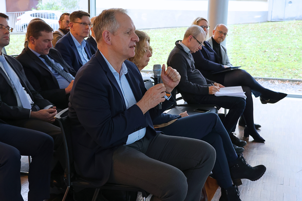 Man sieht einen Mann in einem Publikum, der in ein Mikrofon spricht.