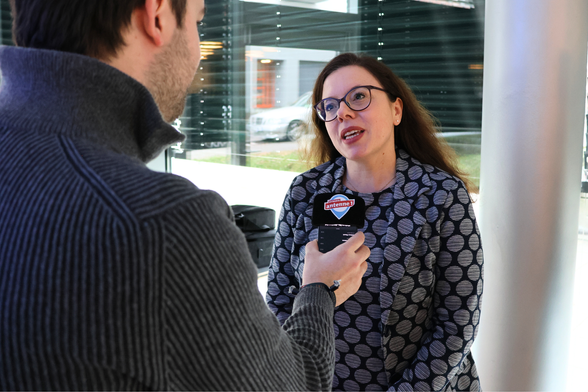 Ein Redakteur hält ein Mikrofon. Er interviewt Ministerialdirektorin Leonie Dirks, die auf seine Fragen antwortet.