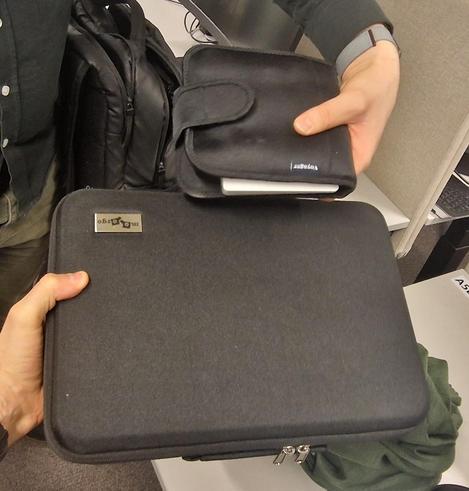 Two black carrying cases, one for the Zsa Voyager split keyboard and another for the MoErgo Glove80. The Voyager case is ¼ to the size/volume of the Glove80s.