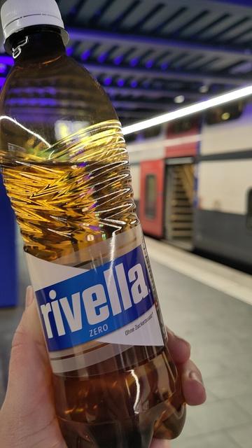A bottle of Rivella Blue (zero) tilted again a swiss SBB-train at the Zürich airport train station