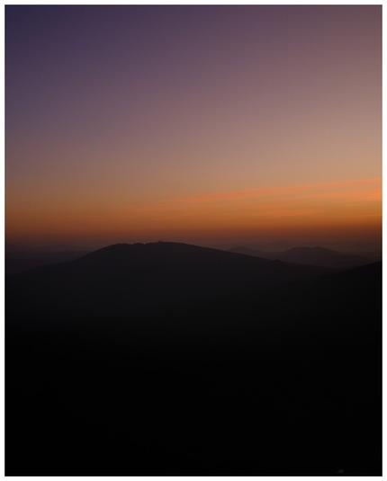 A photo of a sunrise with a mountain