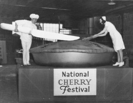 two people cutting into giant cherry pie
