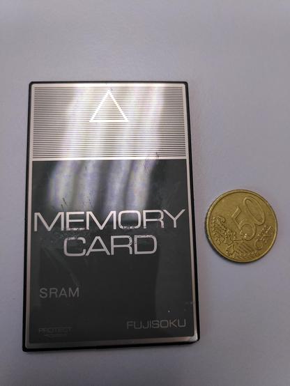 A flat and partially silvery shiny card besides a 50 euro cents coin.