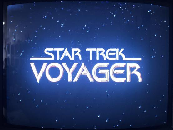 A photo of the opening titles of Star Trek: Voyager playing on a VHS cassette and displayed on a CRT TV. The show’s logo is shown on a star field background.