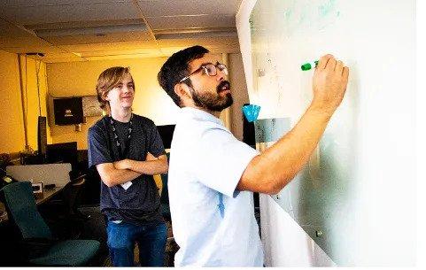 students doing physics at the whiteboard in los alamos