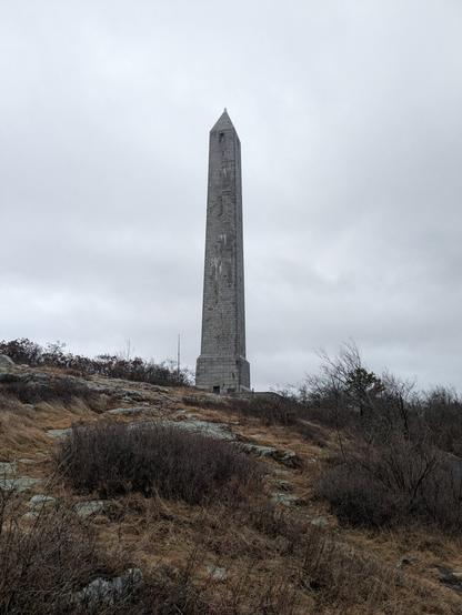 The High Point New Jersey monument, from a hiking train, brown vegetation is visible in the foreground