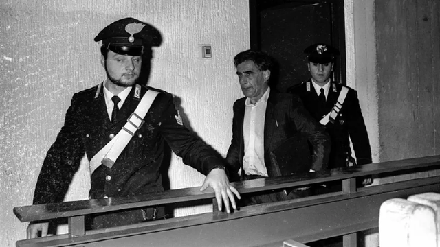 Photo noir et blanc du personnage de Don Mario (Franco Piperno) extrait de sa cellule par deux carabiniers.
