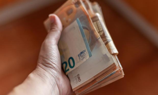 Una persona, sosteniendo un fajo de billetes. (Getty Images)