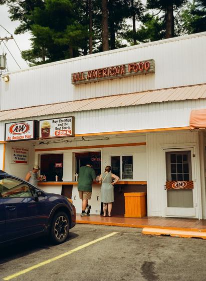 A couple stands at the window of an A&W restaurant.
