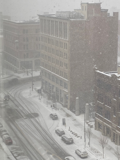 Color image of Downtown Akron, Summit County, Ohio, USA. Image shows heavy snow falling at the intersection of Main and Market Streets, cars and streets and sidewalks snow-covered, the falling snow creating a veil of white pixellation over the scene.