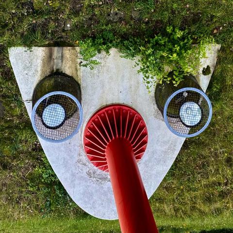 Fundament eines beleuchteten Brückenpfeilers. Sieht aus wie ein Gesicht mit einer langen roten Nase.