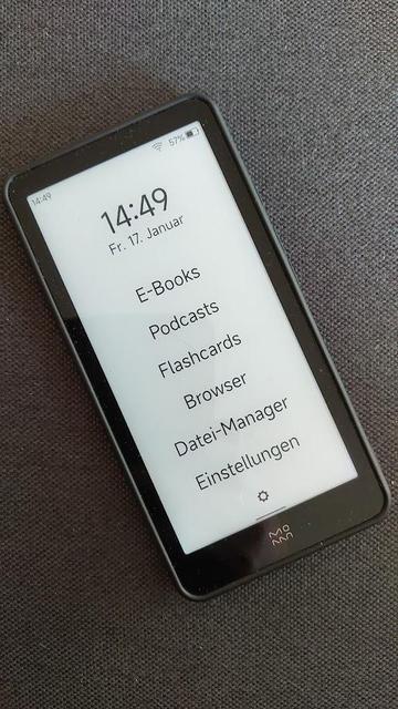 Der InkPalm Plus Reader zeigt das Hauptmenü mit Optionen wie "E-Books", "Podcasts", "Flashcards", "Browser", "Datei-Manager" und "Einstellungen" auf einem minimalistischen Interface.