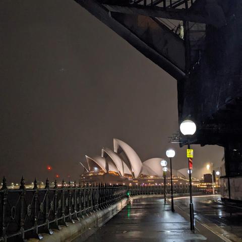 The Sydney Opera House seen from under the trusses of the Harbour Bridge on a dark night