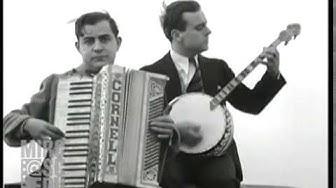 A musician described by the label on his piano accordion as Cornell plays his squeezebox while another dapper fellow strums a banjo next to him.