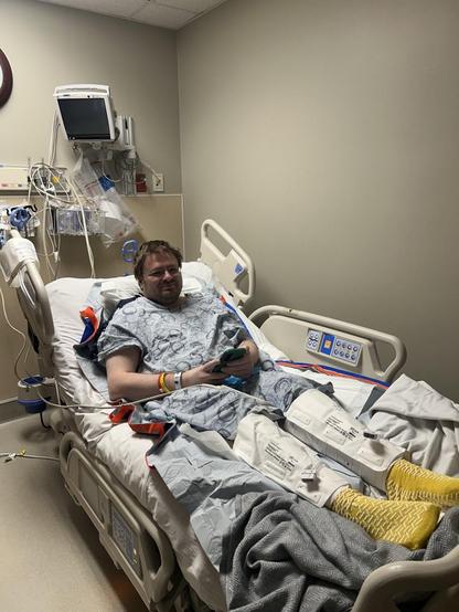 Me laying in a hospital bed the next day, this time in a gown in a pre-op room, awaiting surgery.