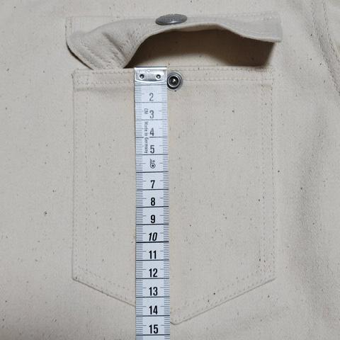 Pocket on an off-white sateen jacket with a tape measure along the length of the pocket