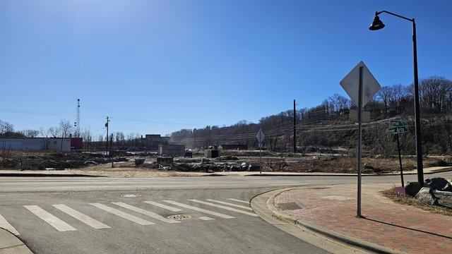 Flood debris consisting of remains of artists' studios and display spaces. On the right is a street sign for the intersection of River Arts Pl. and Lyman St.