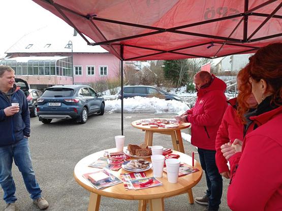 Ein Pavillion der sozialdemokratischen Partei Österreichs. Mehrere Personen in roten Jacken unterhalten sich. Eine Person trinkt Glühwein aus einem Becher