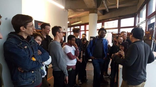 During an exhibition tour the 10 - 15 people are watching the guide (the developer). Most people laughing, enjoying the experience.