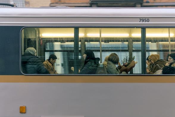Photo of tram passengers, taken through the tram window from outside.
