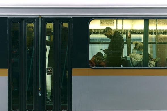 Photo of tram passengers, taken through the tram window from outside.
