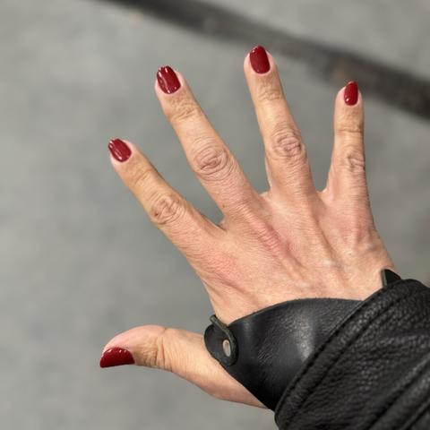 Mano izquierda extendida, también, con unas uñas rojas preciosas
