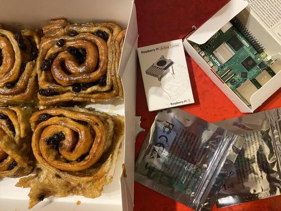 some syrup covered chelsea buns in a box and assorted single board computers of the raspberry pi variety