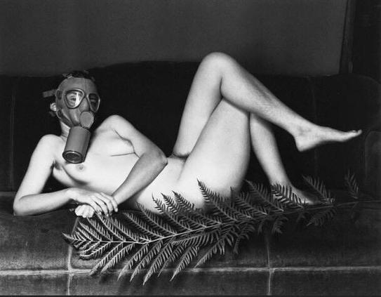 nude woman in gas mask with fern leaf, recumbent