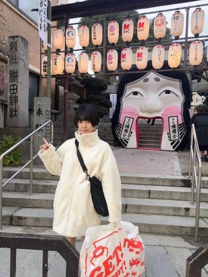 Chiyo on steps with bag. Lanterns in background up the steps