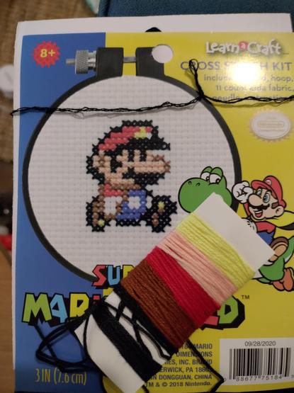 Cross stitch packet cover featuring Super Mario with threads on top