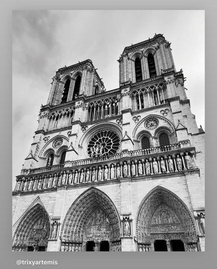 Black and white image capturing the entire front façade of Notre-Dame Cathedral in Paris. Dominating the Gothic structure are its twin bell towers, each topped with intricate stone pinnacles. The grand central doorway is elaborately carved, flanked by two smaller portals, all adorned with detailed religious sculptures. Above the central door is the famous Rose Window, circular and delicate, featuring intricate stone tracery. This architectural masterpiece, with its verticality and intricacy, evokes a sense of timeless grandeur and reverence. The façade's overall symmetry and ornate details stand out, even in monochrome. No people or modern objects are visible, allowing the viewer to focus entirely on the majestic Gothic architecture. There are pockets of grey clouds in the sky above the cathedral.