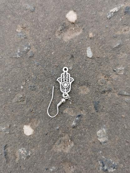 Litter. Lost earing. A silver Hamsa symbol.