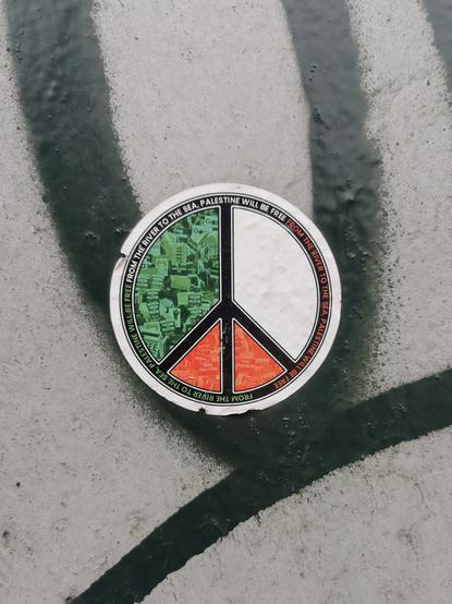 Sticker on a wall. Peace symbol with the colours of the Palestinian flag.