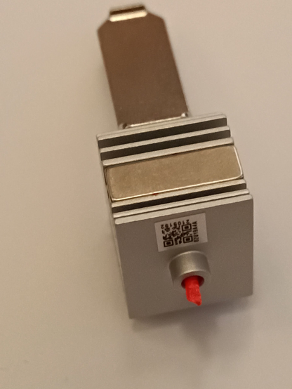 Une buse d'impression 3D, c'est une pièce métallique de 4cm de haut, constituée d'une partie "radiateur" en haut, avec un aimant à l'arrière pour le placement, et un cylindre vertical, avec un bord plat, en dessous, qui conduit le filament liquide vers la surface d'impression.

A l'entrée (en haut) une section de cable rouge dépasse.