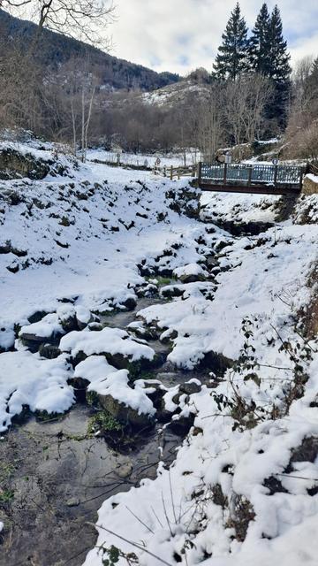 La Riera de Rotjà, envoltada d'un paisatge nevat. Un petit pont la travessa.