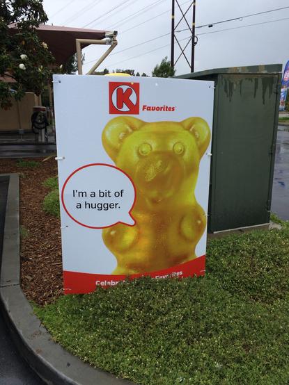 A large picture of a golden gummy bear, which appears to have breasts and no arms. Ironically there’s a text balloon saying “I’m a bit of a hugger.”