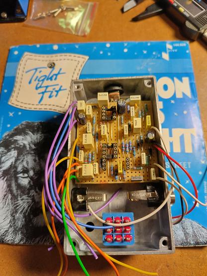 Photo of the inside of a guitar effect placed on top of a 7" single from the band Tight Fit.