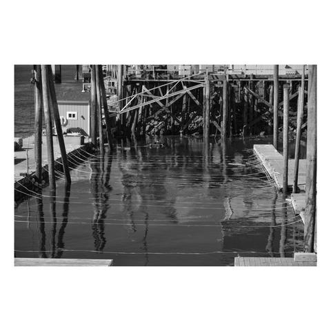 lobster storage facility below docks in maine with ropes evenly spaced across the water