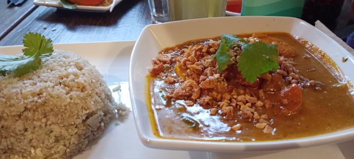 A pile of cauliflower rice and a bowl of curry, both topped with coriander
