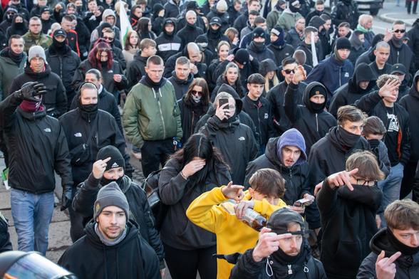 Übersichtsaufnahme von einem Teil des Aufmarsches. Demonstrierende zeigen "White Power"-Gesten und versuchen gleichzeitig ihr Gesicht zu verdecken.
