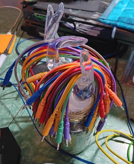 Transparent jewelry display hand holding multicolored, eurorack patch cables.