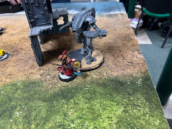 A grey unpainted Armiger Warglaive in combat with my black, gold and red Custodian terminator with a blue glowing electric power axe.