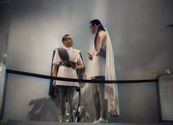 two MEN OF THE FUTURE! in their shoulder extensions and togas and capes, colourised above a glass balcony railing but not below.