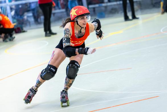 Roller Derby, a jamming person from team Spain in corner 2 skating dynamically